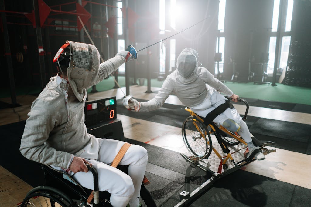 A side view on Two paralympic athletes wearing fencing mask while competing on wheelchairs